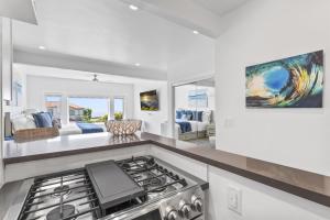 a kitchen with a stove top oven next to a living room at Ocean VIEWS Steps from Victoria Beach Lux Design in Laguna Beach