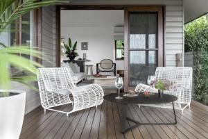 eine Veranda mit weißen Korbstühlen und einem Tisch in der Unterkunft Cape Vue - Vue 5 Byron Bay in Ewingsdale