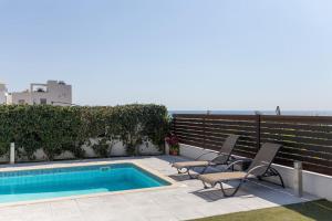 a swimming pool with two chairs sitting next to a fence at Villa Orchid - Luxury 3BR Retreat between Paphos & Coral Bay in Kissonerga