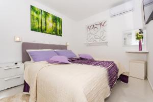 a white bedroom with a bed with purple pillows at Agava Lux in Trogir