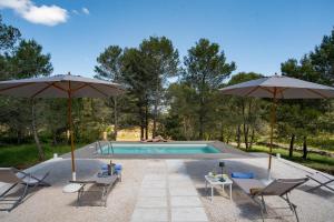 ein Pool mit zwei Sonnenschirmen und zwei Stühlen in der Unterkunft Puglia Essence - Ancient Lamia & Exclusive Pool in Martina Franca