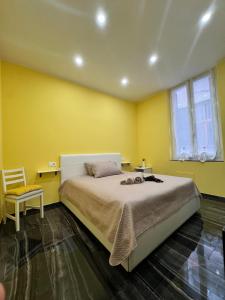 a yellow bedroom with a bed and a chair at Il tulipano in Ventimiglia