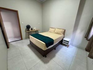 a bedroom with a bed with a green blanket on it at Casa Em Goiânia - Bairro Capuava in Goiânia