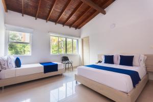 a bedroom with two beds and a table and windows at Hotel Suite del Parque in Medellín