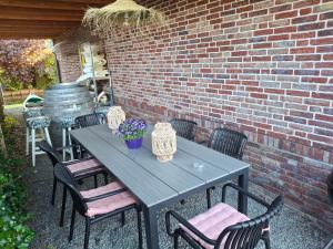 a picnic table with chairs and a brick wall at Huisje Suus, inclusief jacuzzi, kano en kajak in Zuid-Scharwoude