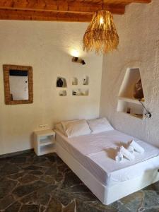 a bedroom with a white bed with a chandelier at Fay's Guesthouse Aegina in Egina