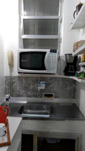 a microwave and a sink in a kitchen at Espaço DéboraMa&Deise in Rio de Janeiro