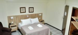 a hotel room with a bed with two white pillows at Goldmen Business Criciúma in Criciúma +81 photos