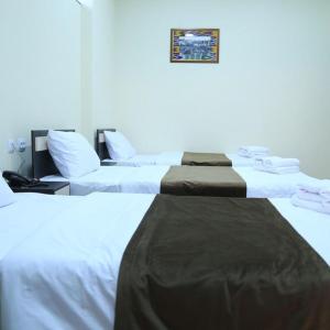 Dos camas en una habitación con paredes blancas. en Panorama Hotel, en Bukhara
