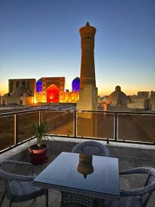 a table and chairs on a balcony with a mosque at GOLDEN MINARET Terrace in Bukhara