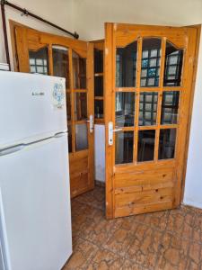 a kitchen with a refrigerator and a wooden door at Căsuța de la linie in Moroeni
