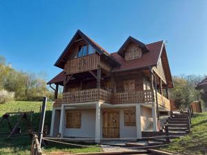 a wooden house with wooden doors and a balcony at Oak House Mrežnica in Duga Resa