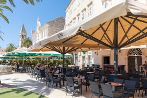 a restaurant with tables and chairs and umbrellas at Agava Lux in Trogir