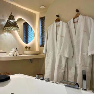 un bagno con accappatoio bianco appeso a un muro di Casa Cinta Évasion Balinaise avec Baignoire Spa a Croix