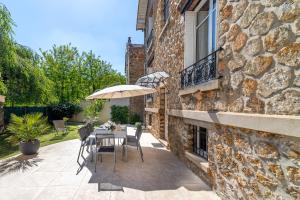 a patio with a table and an umbrella and a building at La Belle Adresse Chic, Calme & Spacieuse in Versailles