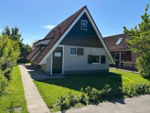 a small house with a gambrel roof at Vakantiehuis nr 165 Lauwersmeer met sauna in Anjum