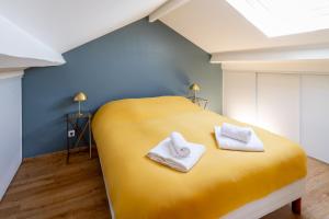 a yellow bed with two towels on top of it at La Belle Adresse Chic, Calme & Spacieuse in Versailles