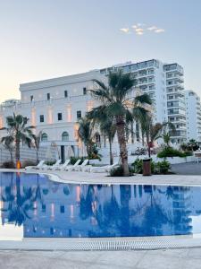a swimming pool in front of a building with palm trees at Caesar Resort & SPA - Apartments with 1 Bedroom in Iskele