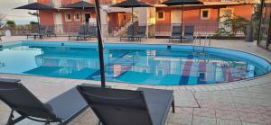 a swimming pool with chairs and umbrellas next to a building at eleni studios in Vlachata