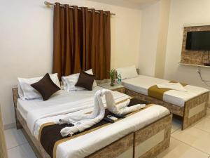 two beds in a hotel room with towels on them at L A V Mansion in Bengaluru