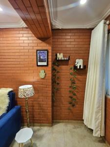 a room with a brick wall with a blue couch at Brick Maison 1BHK with Free Parking, Juhu Bandra in Mumbai