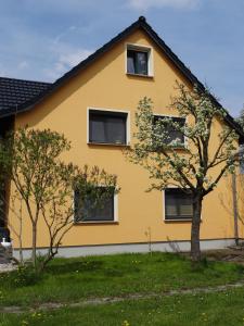 a yellow house with two trees in front of it at Apartment Zum Keulenbergblick in Laußnitz