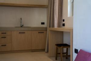 a kitchen with wooden cabinets and a sink and a stool at Wabi Aegean Villa in Ios Chora +11 photos