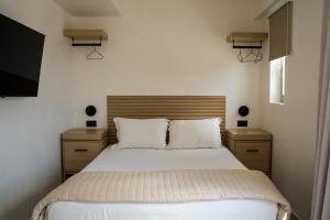 a bedroom with a bed with two night stands and a television at Wabi Aegean Villa in Ios Chora