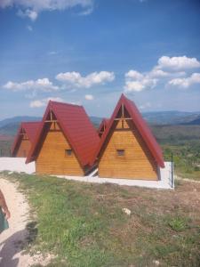 two wooden buildings with red roofs on top of a hill at Bungalovi Potočarska panorama in Mrkonjić Grad