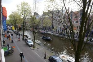 a city street with a river and cars and buildings at Red light district B & B canal view in Amsterdam