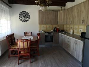 a kitchen with wooden cabinets and a table and chairs at Ezüstfenyő Vendégház in Sárvár