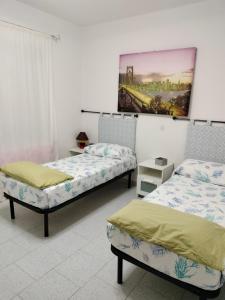 a bedroom with two beds and a painting on the wall at Casa Antony in San Teodoro