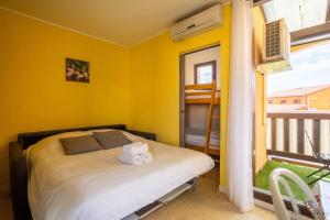 a bedroom with a bed with yellow walls and a window at Studio Yellow Mood - Pond, Beach, Peace & Parking in Le Barcarès