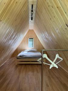 a bed in a wooden room with a ceiling at Domek w lesie in Gnojno