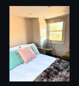 a bedroom with a bed and a window and a chair at Upstairs at Rumblebees in Felsted Station
