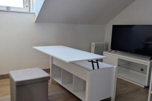 a white desk in a room with a flat screen tv at Studio 3 Lumineux in Sarreguemines