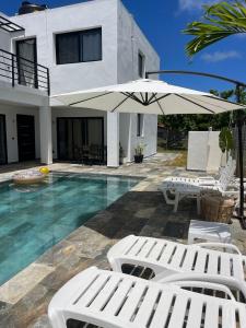 a villa with a swimming pool with chairs and an umbrella at Casa Entre Playas con piscina en Las Galeras in Las Galeras