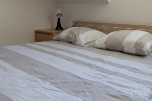 a white bed with two pillows on top of it at Studio 3 Lumineux in Sarreguemines
