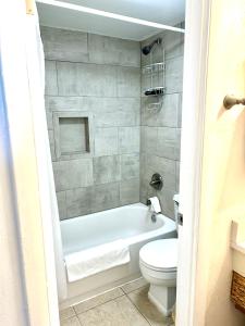 a bathroom with a white tub and a toilet at Beach Condo with Pool & Tiki Bar! in Daytona Beach +19 photos