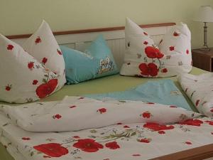 a bed with white pillows and red flowers on it at above painters studio in Pirna