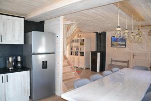 a kitchen and dining room with a refrigerator and a table at Chalet des Aigrettes, Les 1000 Etangs in La Voivre