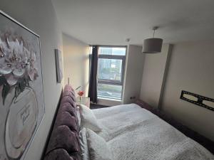 een slaapkamer met een bed en een groot raam bij Ventro Apartments LIVERPOOL in Liverpool