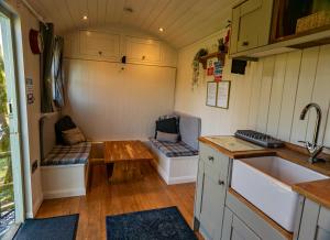 a small kitchen with a table and benches in a caravan at Lavender Retreat with Private Hot Tub in Upper Hulme