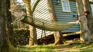 a hammock hanging between two trees in front of a house at Lavender Retreat with Private Hot Tub in Upper Hulme