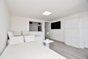 a white bedroom with a white bed and a tv at House Luxury in Matulji