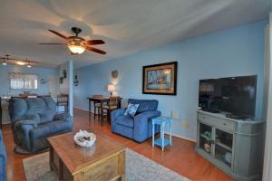 a living room with two blue chairs and a flat screen tv at Topsail Dunes 2308 in Chadwick Acres