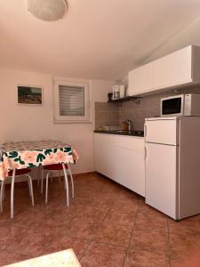 a kitchen with a table and a white refrigerator at Apartmani Šehović in Borovići