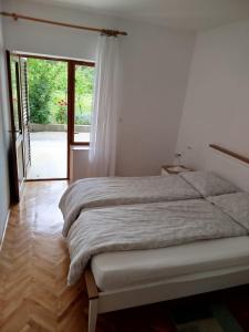 a white bedroom with a bed with a window at Brine in Starigrad-Paklenica +42 photos