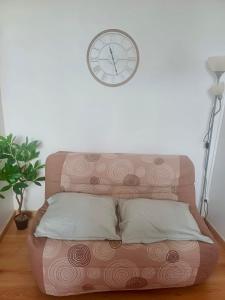 a clock on the wall above a couch with a pillow at Le minimaliste in Pamiers +16 photos