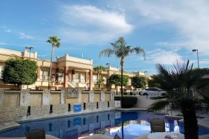a swimming pool in front of a building with palm trees at Royal Palace in Hermosillo